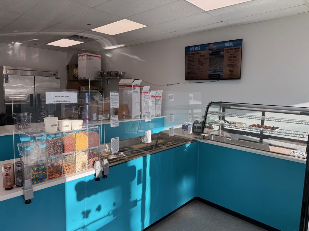 Picture of inside of Doughzerts store, showing their toppings, dough flavors, and refrigerated case.
