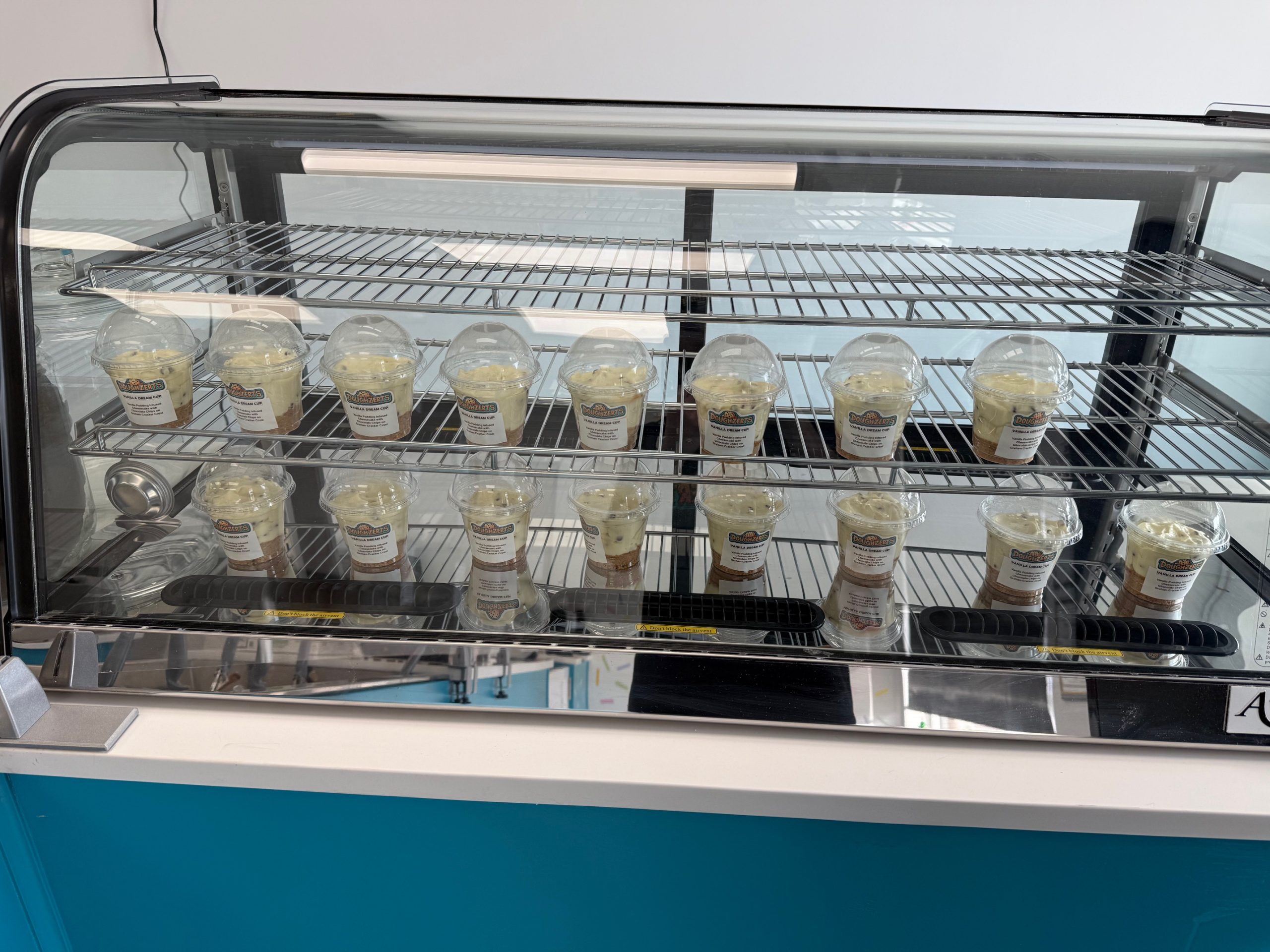 Picture of Doughzerts' "Dream Cup" cheesecake cups inside their refrigerated case.